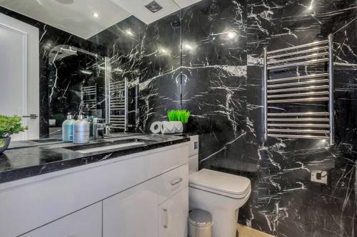 uma casa de banho em mármore preto com um WC e um lavatório em Modern One Bed Serviced Apartment in Chelsea em Londres