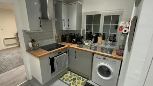 a kitchen with a sink and a washing machine at Entire One Double Bedroom apartment in London