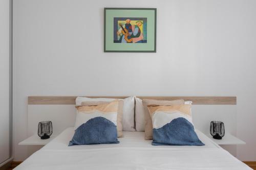 - une chambre avec un lit blanc et des oreillers bleus dans l'établissement Sunny 1BDR with Balcony & Parking, à Zagreb