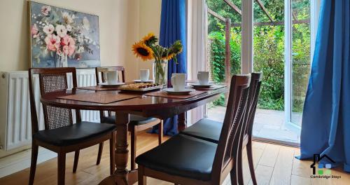 a dining room table with chairs and a vase of flowers at Cambridge Stays 3BR House-Garden-Lots of Parking-15 min to City Center- Close to Cambridge Science park in Cambridge