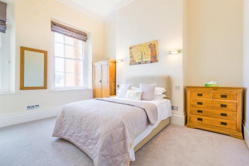 a bedroom with a bed and a dresser and a window at Croft House - By Luxury Apartments in Cheltenham