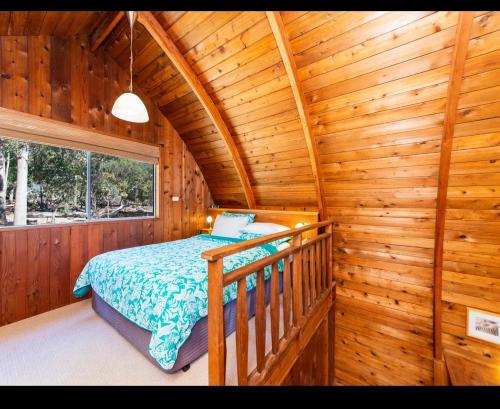 a bedroom with a bed in a log cabin at Jarrah Glen Cabins in Nannup