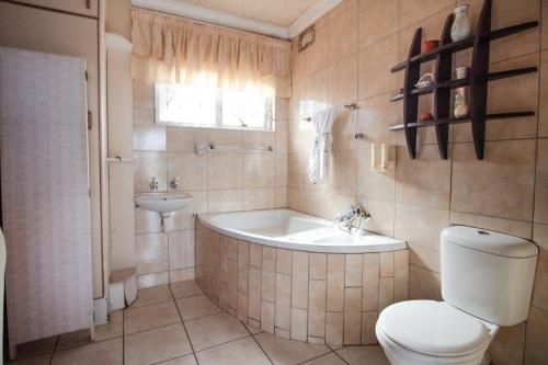 a bathroom with a tub and a toilet and a sink at Nolapeace B&B in East London