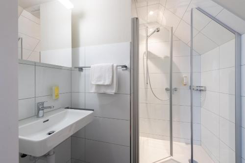 a white bathroom with a sink and a shower at Hotel Garni Rössli in St. Gallen