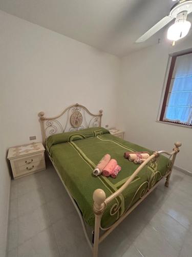a bedroom with a green bed with two dolls on it at PM 15 Via Liguria Guest House in Alghero
