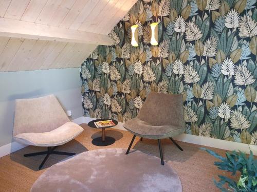 two chairs and a table in a room with a wallpaper at B&B De NieuwenHof 'De Tuinkamer' in Melderslo