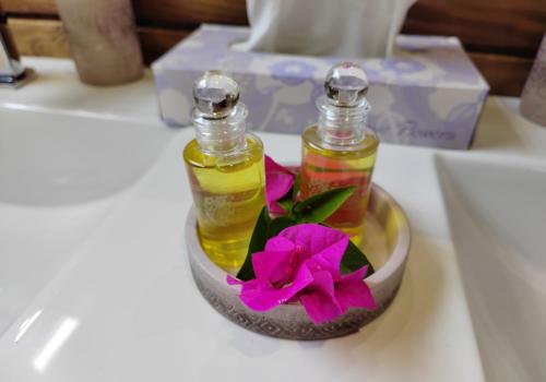 two bottles of essential oils and a flower on a table at Odyssea Caraïbes Cottages & Spa in Saint-Louis