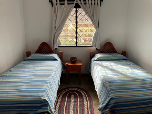 two beds in a small room with a window at Villa 23 in Malindi