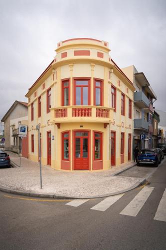 um edifício amarelo e vermelho na esquina de uma rua em A'MAR by Alojamento Ideal na Póvoa do Varzim