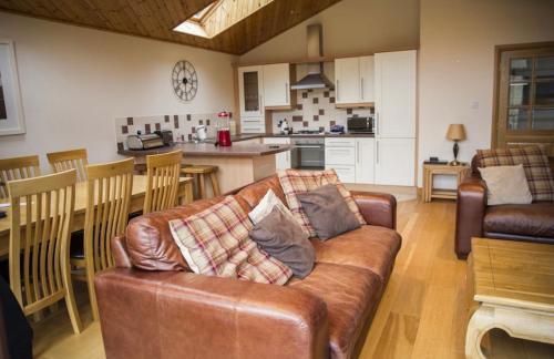 a living room with a leather couch and a kitchen at Na Craigean Lodge in White Bridge