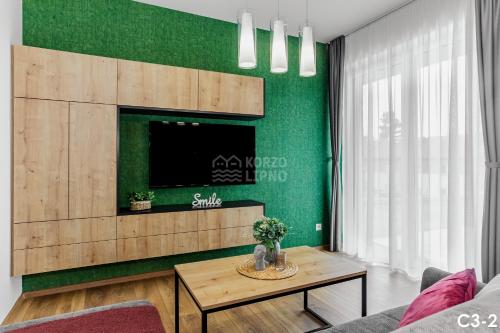 a living room with a green wall with a tv at KORZO LIPNO C in Lipno nad Vltavou