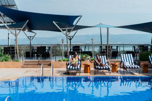 two people sitting in chairs next to a swimming pool at Acacia Premier Hotel in Kisumu