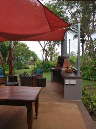 a patio with an outdoor grill with a red umbrella at Casa Jardim in Vilanculos