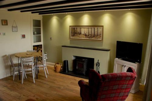 uma sala de estar com uma mesa e uma lareira em Cwmwl Gwyn Cottage in the heart of the old town em Llantrisant