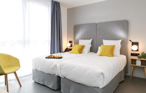 a bedroom with a large white bed with yellow pillows at Odalys City Angers Centre Gare in Angers