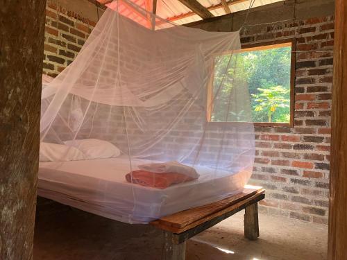 Łóżko w pokoju z moskitierą w obiekcie Villa Medici Macarena, finca eco-turistica 