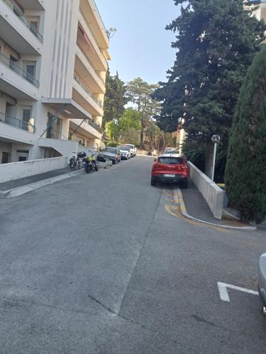 une voiture rouge garée dans un parking à côté d'un bâtiment dans l'établissement Nice centre- small pied-a-terre near beaches, à Nice
