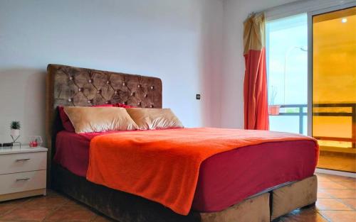 1 dormitorio con 1 cama grande con manta naranja en Rouge Plage Studio, en Agadir