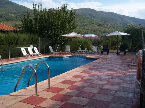 einen Pool mit Stühlen und Sonnenschirmen auf einer Terrasse in der Unterkunft Casa Rural Josefina 1 y 2 in Navaconcejo