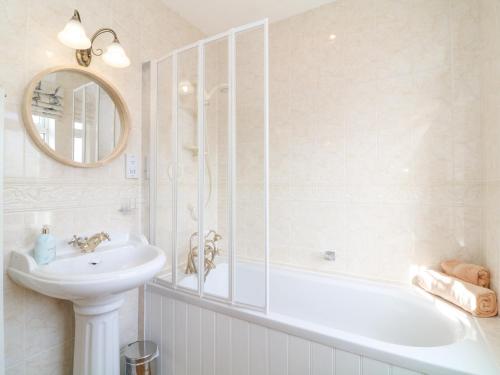 a white bathroom with a sink and a tub and a mirror at Marine Cottage in Salcombe