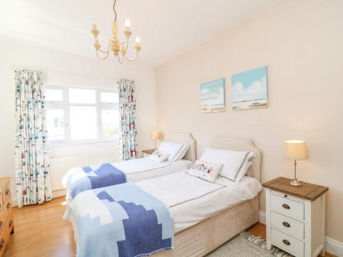 two twin beds in a bedroom with a chandelier at Marine Cottage in Salcombe