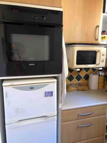 a kitchen with a microwave and a stove top oven at Agréable T2 avec toit terrasse face à la plage in Sausset-les-Pins
