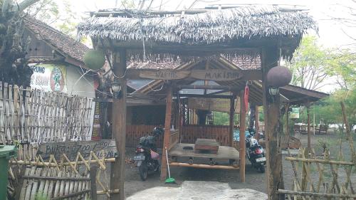 una pequeña cabaña con una motocicleta estacionada frente a ella en Omah mak isun pulau santen, en Banyuwangi