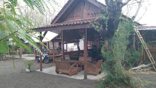 un pequeño edificio con bancos delante en Omah mak isun pulau santen, en Banyuwangi
