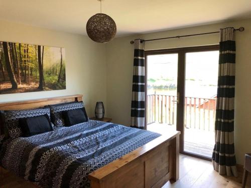 a bedroom with a bed and a sliding glass door at Lochside Lodge in White Bridge