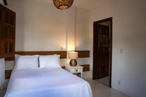 um quarto com uma cama e um candeeiro sobre uma mesa em Pousada Canto do Sol em Barra Grande