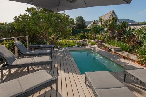 a swimming pool with two chairs and an umbrella at Absolute Ocean Boutique Guesthouse in Hermanus