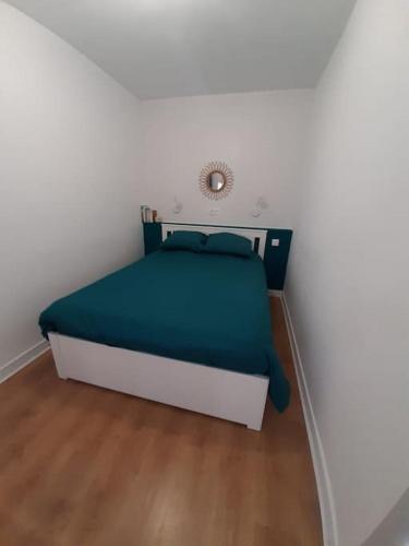 un petit lit dans une chambre blanche avec une couverture bleue dans l'établissement Appartement 3* joliment rénové à 150m des thermes, à Luchon