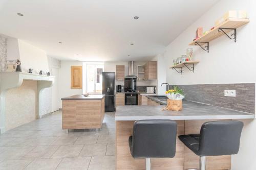 - une cuisine avec un comptoir et 2 chaises dans l'établissement Le Grand Pressoir - Grande maison avec jardin, à Nanton