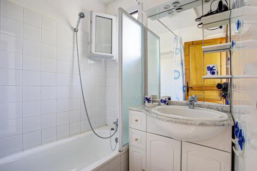une salle de bain blanche avec un lavabo et une douche dans l'établissement Maisonnette du Clos - Avec piscine partagée, à Argelès-sur-Mer