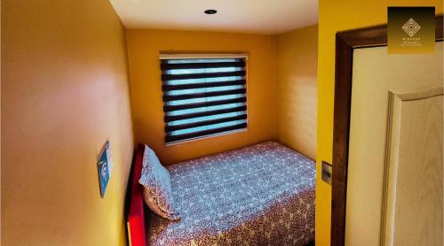 a small bedroom with a bed and a window at Hostal Mirador Quellón in Quellón