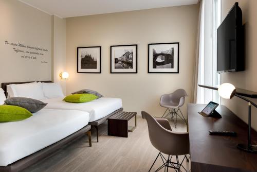 a bedroom with two beds and a desk and a tv at Hotel Canada in Milan