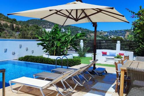 a patio with an umbrella and chairs and a pool at Bodrum merkez'de Havuzlu, Saunalı, müstakil villa in Bodrum City