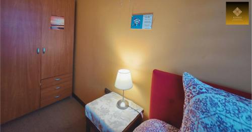 a bedroom with a bed and a dresser and a lamp at Hostal Mirador Quellón in Quellón