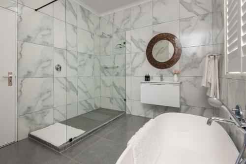 ein Bad mit einer Dusche, einer Badewanne und einem Waschbecken in der Unterkunft Absolute Ocean Boutique Guesthouse in Hermanus