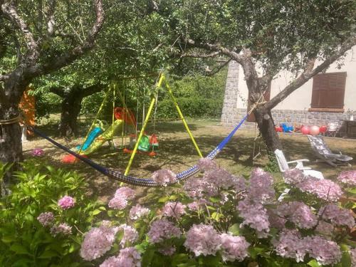 a swing set in a yard with flowers at Charmant T2 dans chalet familial in Valdeblore