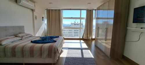 een slaapkamer met een bed en een groot raam bij Centro de SP, vista p/ ZN in Sao Paulo