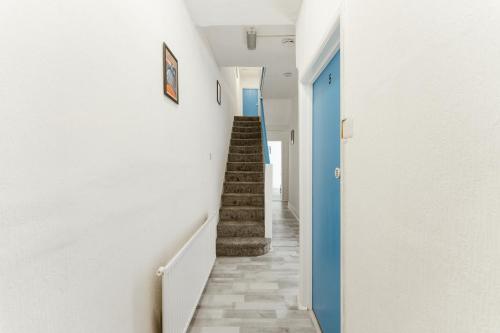 a hallway with stairs and a blue door at Leyton Comfy Double rooms -50 in London