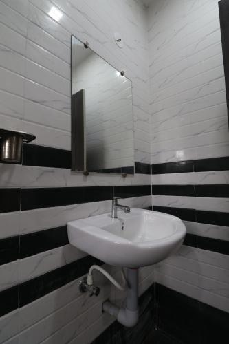 lavabo blanco en el baño con espejo en HOTEL VALLABHA RESIDENSY en Rajahmundry