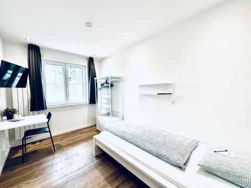 a white bedroom with a bed and a desk at Monteurzimmer - Worker's accommodation - ZIMMERzuVERMIETEN in Bäriswil in Bäriswil