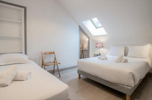 une chambre blanche avec deux lits et une chaise dans l'établissement Refuge centre ville avec parking, à Annecy