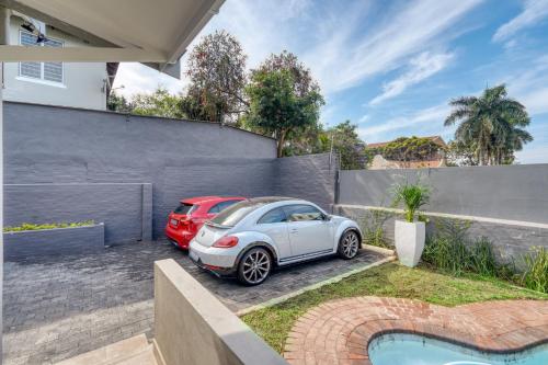 two cars parked in front of a house at Hampton Collection - Contemporary 3 Sleeper Apartment with Pool in Durban