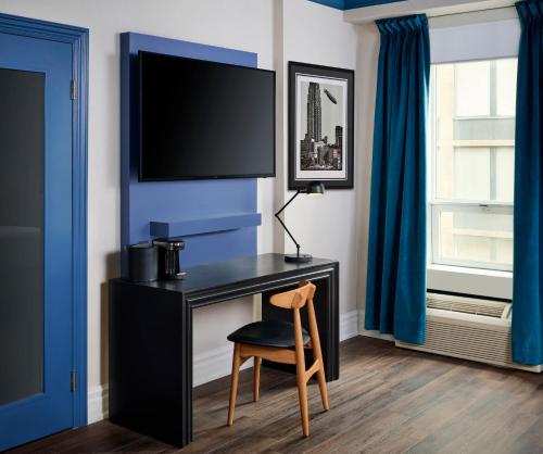 a room with a desk with a chair and a tv at Hotel Victoria in Toronto