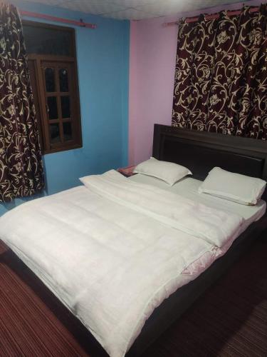 a large white bed in a blue room at Hotel Swornim Namobuddha in Dhulikhel
