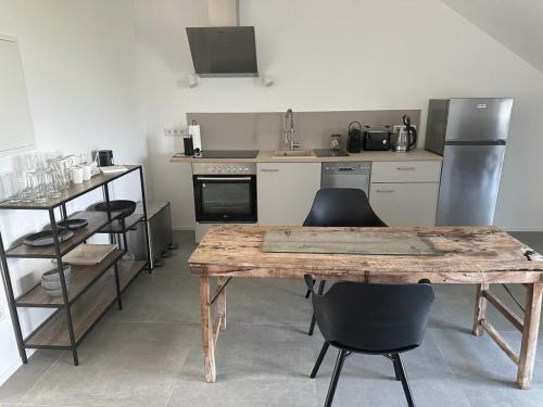 a kitchen with a wooden table and chairs at Hof Busen Landhaus Ap. oben links in Mönchengladbach