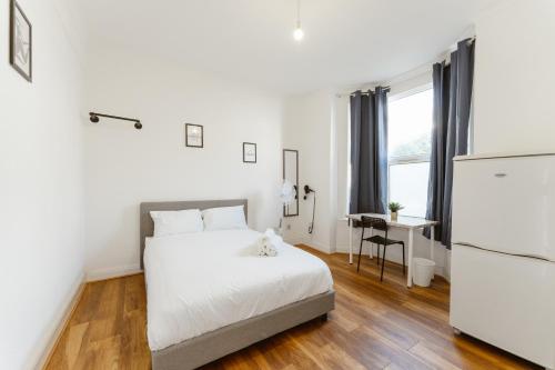 Leyton Comfy Double rooms - 50 في لندن: غرفة نوم بيضاء فيها سرير وثلاجة